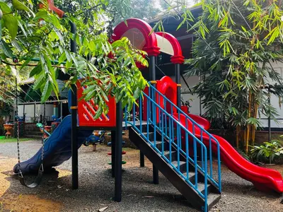 a playground with a red slide in a park at Flavoury Restaurant & Rooms in Paithalmala