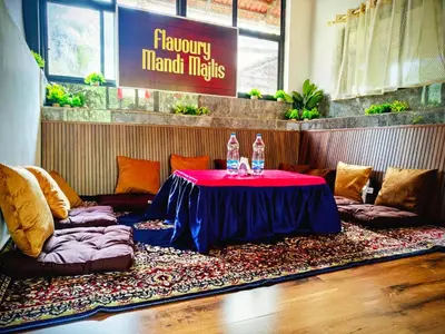 a table and couches in a room with a table and chairs at Flavoury Restaurant & Rooms in Paithalmala