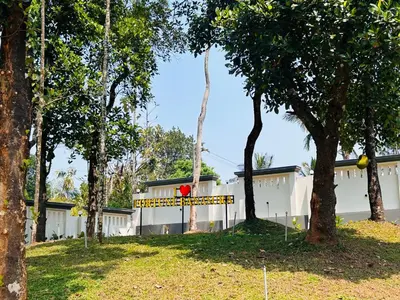 a white building with a sign in front of some trees at FORTUNE BANASURA Resort in Kalpetta
