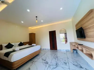 a bedroom with a bed and a flat screen tv at FORTUNE BANASURA Resort in Kalpetta