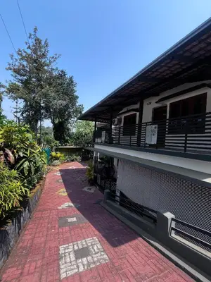 a house with a brick walkway next to a building at Ashique holiday home in Padinjarathara