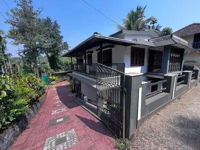 a house with a gate and a red brick sidewalk at Ashique holiday home in Padinjarathara