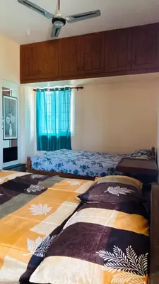 a bedroom with a bed and a window with blue curtains at RoBen Villa in Pollāchi