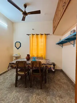 a dining room with a table and chairs and a ceiling fan at RoBen Villa in Pollāchi