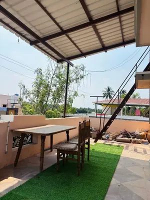 a table and chairs on a patio with grass at RoBen Villa in Pollāchi