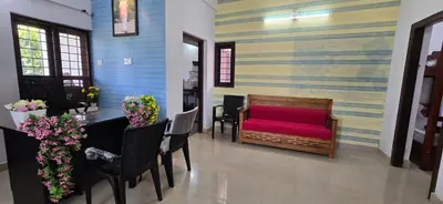 a living room with a red couch and a table at Brighton Hostel Stays in Sultan Bathery