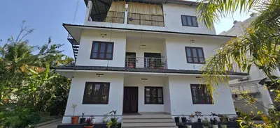 a white house with a staircase in front of it at Brighton Hostel Stays in Sultan Bathery