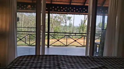 a bedroom with a bed and a large window at Vidman Homey Huts in Tindummal