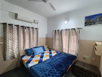 a small bedroom with a bed and curtains at Hazel's ELiTE Homestay 3BHK in Mysore
