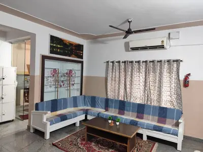 a living room with a blue couch and a table at Hazel's ELiTE Homestay 3BHK in Mysore