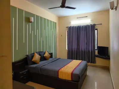 a bedroom with a bed and a window and a television at Hill View Residency in Kalpetta