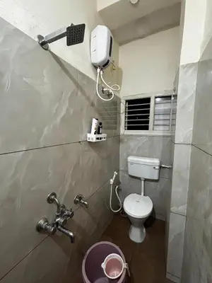 a bathroom with a toilet and a hair dryer on the wall at Hazel's ELiTE Homestay 2bhk in Mysore