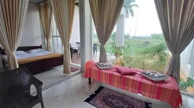 a bedroom with a bed and a large window at GG Home stay in Pollāchi