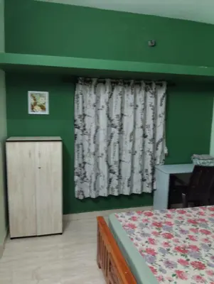 a bedroom with green walls and a bed and a window at Next door in Coimbatore