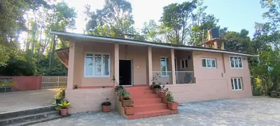 a small pink house with stairs in front of it at Amblyn Home stay coorg in Madikeri