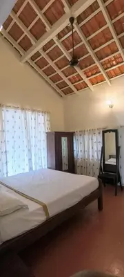 a bedroom with a bed with a chair and a mirror at Amblyn Home stay coorg in Madikeri