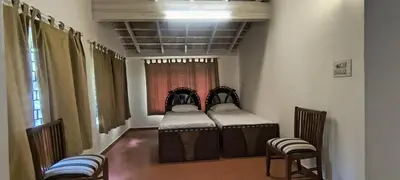 a room with two beds with chairs and a window at Amblyn Home stay coorg in Madikeri
