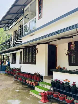 a building with potted plants in front of it at Quiet Canopy homestay in Padinjarathara