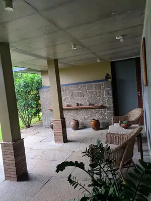 a patio with two chairs and a stone wall at Homestay Namaha in Meppādi