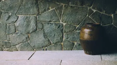 a vase sitting on a table in front of a stone wall at Homestay Namaha in Meppādi