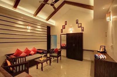 a living room with a couch and red pillows at Gokulam Grand Resort & Spa, Coorg in Kushālnagar