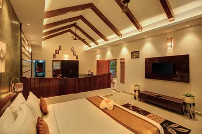 a living room with a large bed and a flat screen tv at Gokulam Grand Resort & Spa, Coorg in Kushālnagar