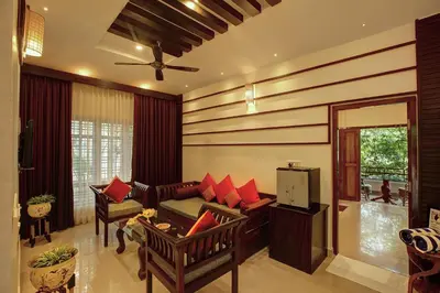 a living room with a couch and red pillows at Gokulam Grand Resort & Spa, Coorg in Kushālnagar