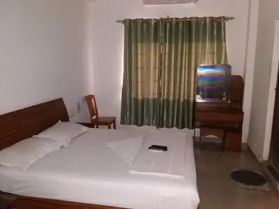 a bedroom with a bed and a tv and a window at Blue Stones Service Apartment in Coimbatore