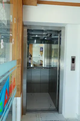 a glass elevator in a building with a person taking a picture at Anna Residency in Nedumbassery