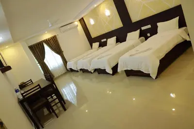 a bedroom with three beds and a table and chairs at Anna Residency in Nedumbassery