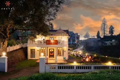 a white house with a table in front of it at night at Zostel Ooty in Ooty