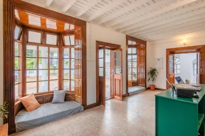 a room with windows and a couch and a desk at Zostel Ooty in Ooty
