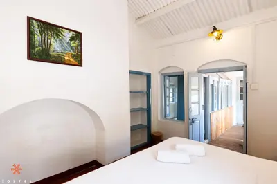 a bedroom with a white bed and a mirror at Zostel Ooty in Ooty
