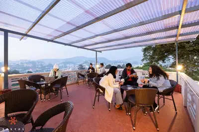 a group of people sitting at tables on a patio at Zostel Ooty in Ooty