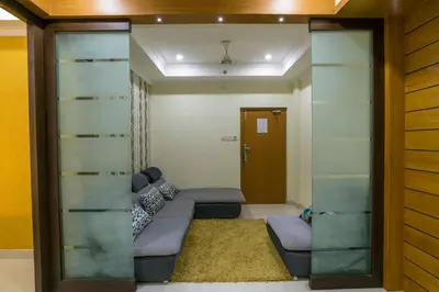 a living room with a couch and a glass wall at Sree Gokulam Residency in Trichūr