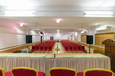 an empty auditorium with red chairs in a room at Sree Gokulam Residency in Trichūr