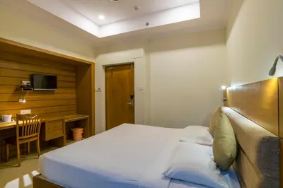 a bedroom with a bed and a desk and a television at Sree Gokulam Residency in Trichūr