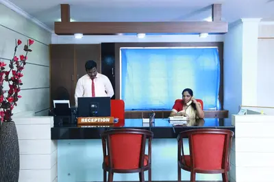 a man and a woman sitting at a desk with a computer at Orison Residency Hotel in Kunnamkulam