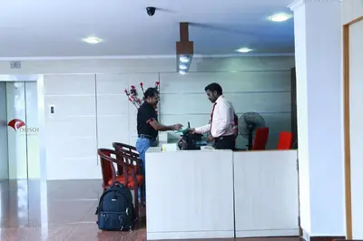 two men shaking hands at a counter in an office at Orison Residency Hotel in Kunnamkulam