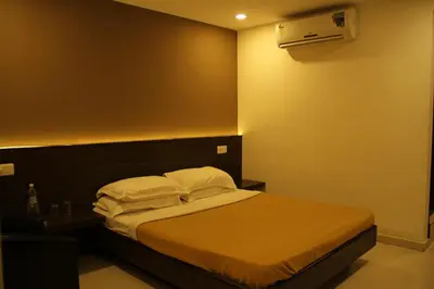 a bedroom with a bed with white sheets and pillows at Sugam Hotel Pvt Ltd in Coimbatore
