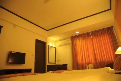 a hotel room with a bed and a flat screen tv at Sugam Hotel Pvt Ltd in Coimbatore