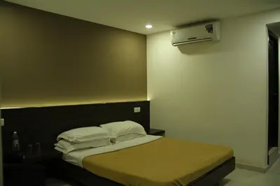a bedroom with a bed with white sheets and pillows at Sugam Hotel Pvt Ltd in Coimbatore