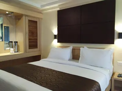a hotel room with a large bed with white pillows at Darshan Hotel in Ooty