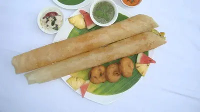 a plate of food with a roll on a banana leaf at Rouba Residency Hotel in Ponnāni