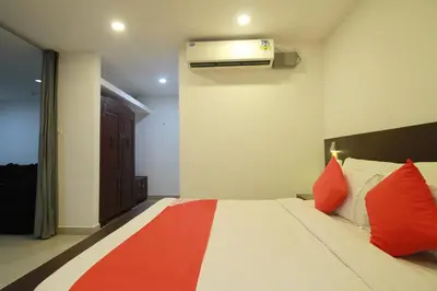 a bedroom with a bed with red pillows and a heater at Half Moon Residency Calicut in Kozhikode