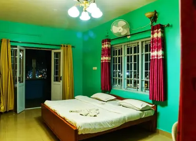 a green bedroom with a bed with red curtains at RK Holiday Home in Ooty