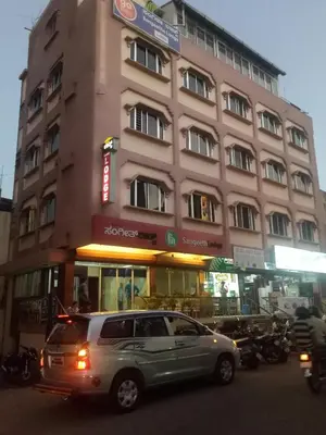 a car is parked in front of a building at hotel sangeeth lodging in Mysore