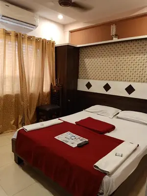a bedroom with a large bed with a red blanket at hotel sangeeth lodging in Mysore