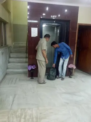 two people standing outside of a door with a bag at hotel sangeeth lodging in Mysore