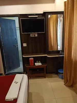 a room with a television and a bed with a table at hotel sangeeth lodging in Mysore
